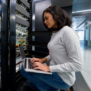 Woman kneeling server racks laptop 1x1